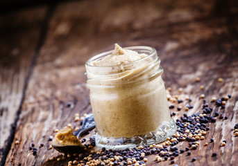 Freshly prepared mustard sauce in a small glass jar with a spoon