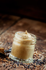 Freshly prepared mustard sauce in a small glass jar with a spoon