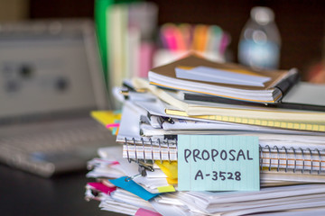 Proposal; Stack of Documents and Laptop at working Desk.