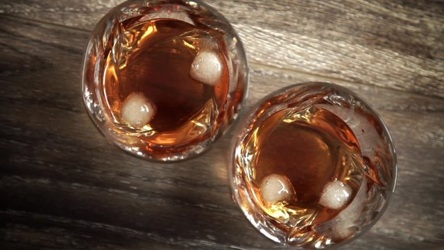 Glasses of whiskey with ice on wooden table. Top view with copy space