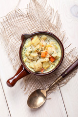 Homemade cauliflower soup in a brown bowl.