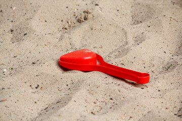 Fototapeta na wymiar Red children scoop left on the sand. Childhood