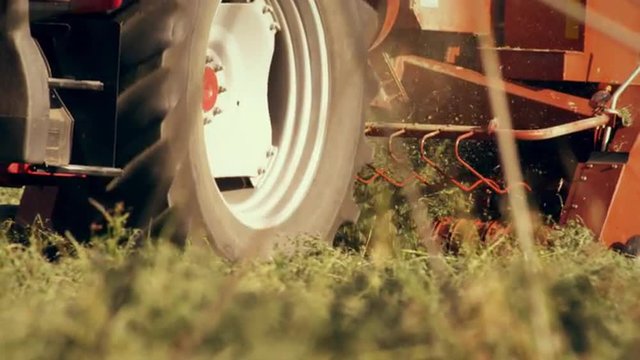 Close-up shot of the bottom of a hay baler as it gathers hay from the ground