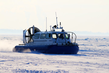 Hovercraft crossing frozen river in the sunny day