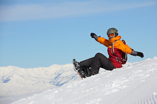 girl with a snowboard sitting on the slope and rejoices