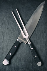 carving knife and fork on black board