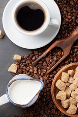 Coffee cup, beans and brown sugar on stone table