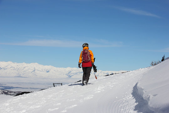 girl with a snowboard walks away along the slope