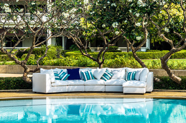 Outdoor sofa with cushions and pillows in the garden by the pool