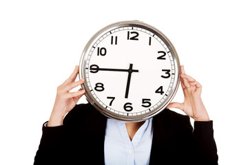 Business woman covering face with a clock