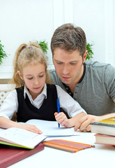Father helping daughter with homework at home.