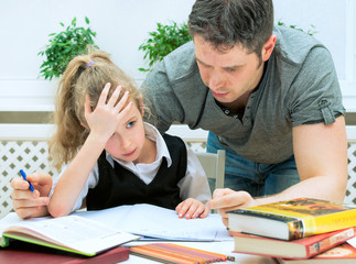 Father helping daughter with homework at home.