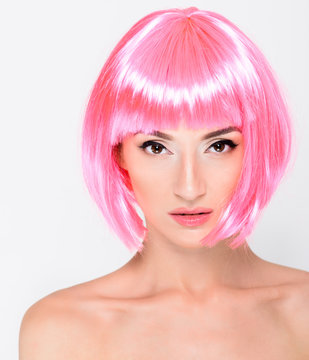 Head shot of young woman in pink wig on white background