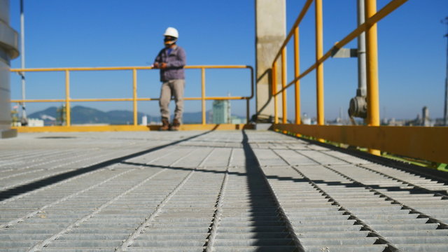 Engineer with safety suit to standing on platform of industrial plant 
