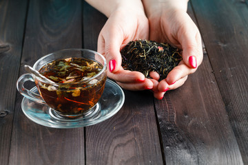 Female hands hold heap of herbal tea