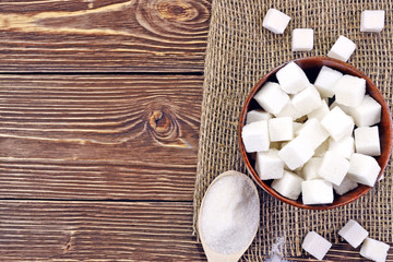 Photo of a wooden spoon and a sugar bowl with sugar on the table