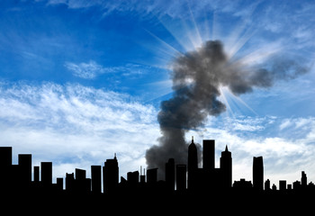 Fototapeta premium Silhouette of the city with smoke against cloudy sky