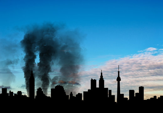 Silhouette of the city with smoke against cloudy sky