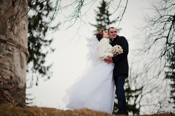 Young wedding couple on winter background stone landskape and wall of old castle
