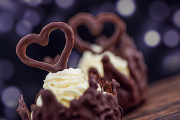 Chocolate desserts filled with white cream and chocolate hearts on it on purple background, valentines day