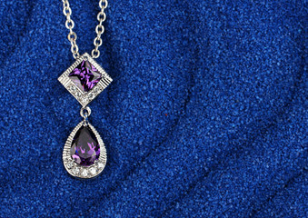 Fototapeta na wymiar colourful Jewelry pendant with gems on dark blue sand waves back