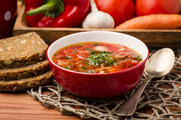 Borsht - traditional russian and ukranian beetroot soup in red bowl on wooden background.