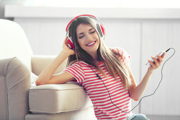 Woman listening music in headphones in room