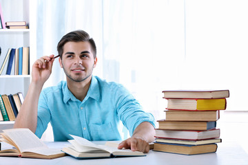 Young man reading book at table in room