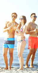 Happy young friends drinking beer at the beach, outdoors