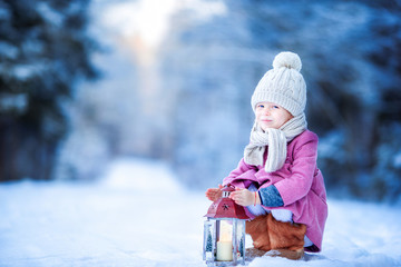 Adorable little girl with flashlight in frozen forest on Christmas outdoors