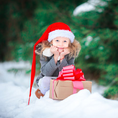 Adorable happy girl with christmas box gift in winter outdoors on Xmas eve