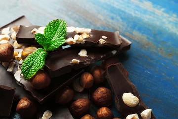 Chocolate pieces with nuts on color wooden background