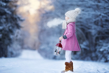 Adorable little girl with flashlight in frozen winter on Christmas outdoors