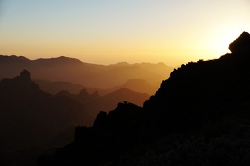 Mountain ridges colored by the setting sun. Silhouettes fading near horizon.