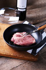 Marbled beef steak and wine bottle on wooden background