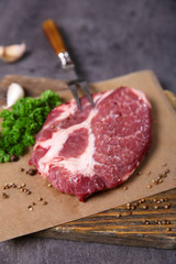 Marbled beef steak and spices on wooden background
