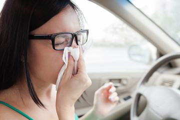 Woman blowing nose into tissue
