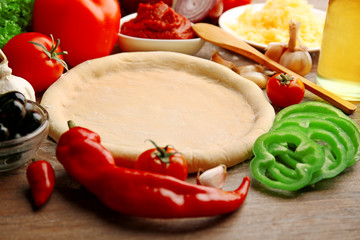 Dough basis and ingredients for pizza, on the table