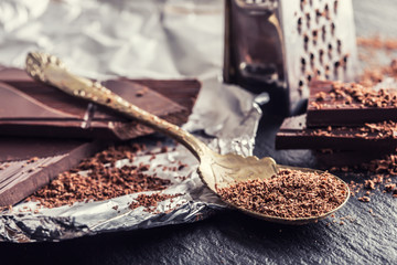 Chocolate. Black chocolate. A few cubes of black chocolate. Chocolate slabs spilled from grated chockolate powder.