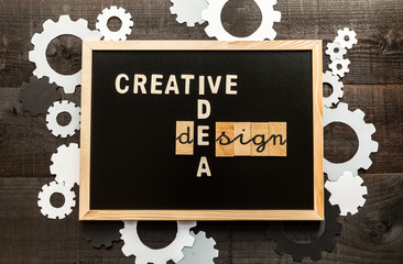 Wooden letters on slate and wood background with a concept message about design concept and gearwheels