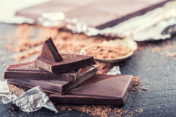 Chocolate. Black chocolate. A few cubes of black chocolate. Chocolate slabs spilled from grated chockolate powder.