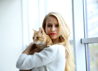 Young woman holds red cat in hands, close up