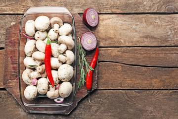 Marinating mushrooms with spices on wooden table