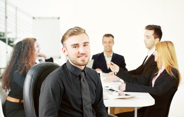 Photo of a young business man with his staff at the meeting in a conference room