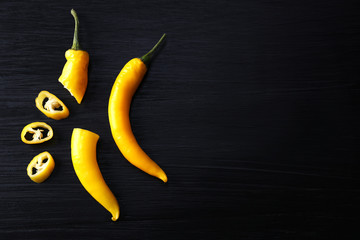 Yellow chili peppers on dark wooden background