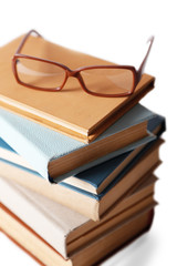 Pile of books and eyeglasses on it isolated on white background