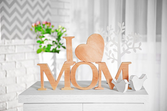 I love mom inscription of wooden letters with heart on a white table