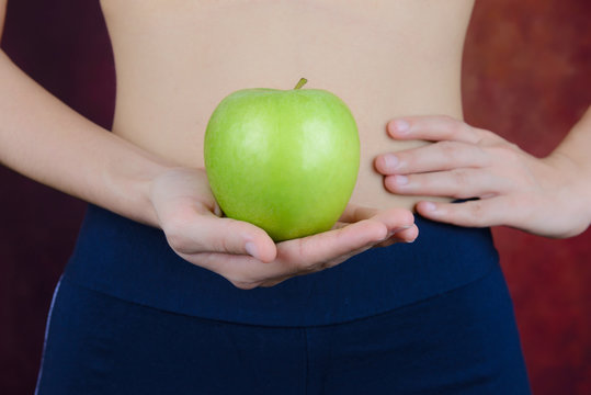 slim woman carries green apple in hand