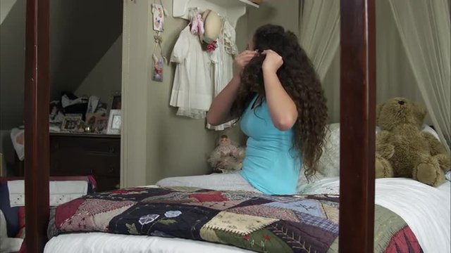Slow motion of girl putting a barrette into her hair.