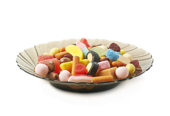 Glass plate full of candies isolated